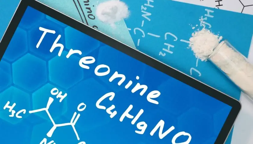 Tablet z napisem "Threonine" i wzorem chemicznym. Obok proszek w probówce i na kartce.