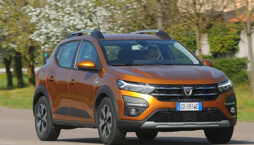Dacia Sandero Stepway arancione in movimento, con alberi fioriti sullo sfondo. Nonostante i suoi pregi, alcuni difetti Dacia Sandero Stepway sono noti.