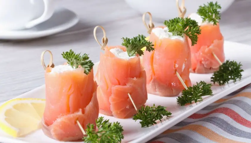 Rotolini di salmone affumicato con formaggio cremoso e prezzemolo, perfetti per ricette fredde.