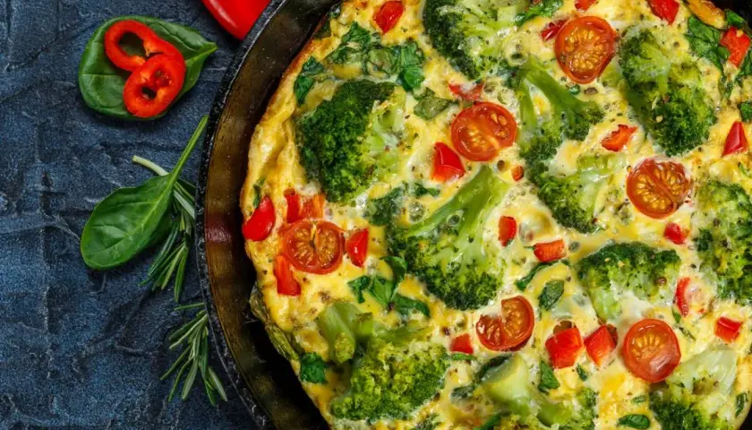 Pyszny omlet z warzywami: brokuły, pomidorki koktajlowe i papryka w złocistym jajku.