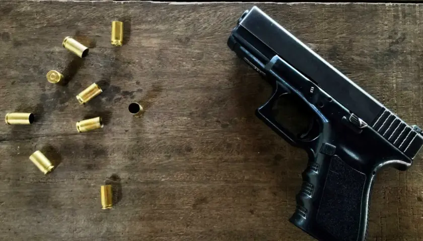 Czarny pistolet i łuski na drewnianym stole. Jaka broń na pozwolenie kolekcjonerskie?