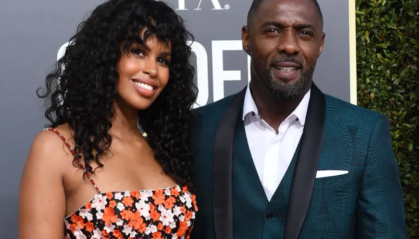 Idris Elba z żoną, Sabriną Dhowre, na czerwonym dywanie. Ona w kwiecistej sukience, on w eleganckim garniturze.