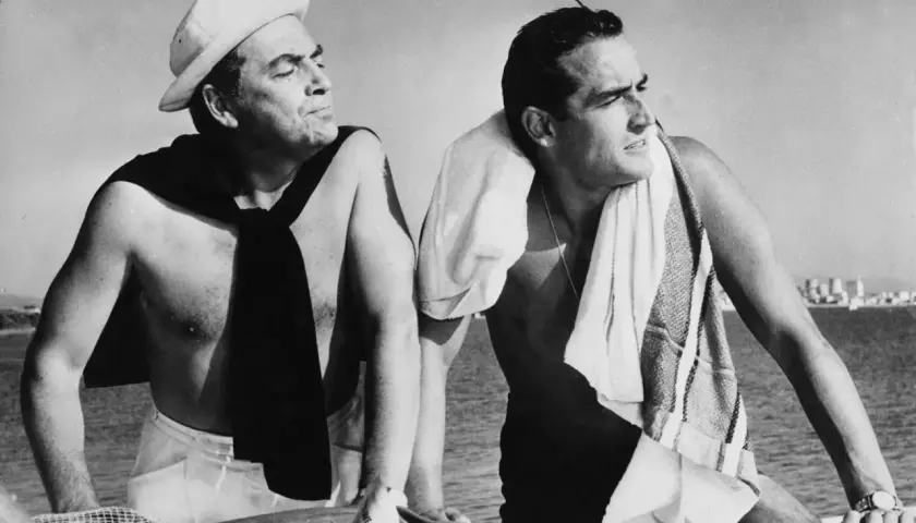Due uomini su una barca, uno con un berretto da marinaio e una sciarpa, l'altro con un asciugamano. Un'immagine che evoca il significato del sorpasso, film e vita.