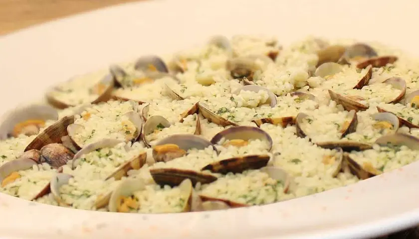 Delicioso arroz con almejas, un plato de marisco cremoso y lleno de sabor, adornado con perejil fresco.