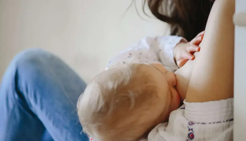 Mamma allatta il suo bambino, dimostrando che si può allattare con la febbre. Un momento di amore e cura.