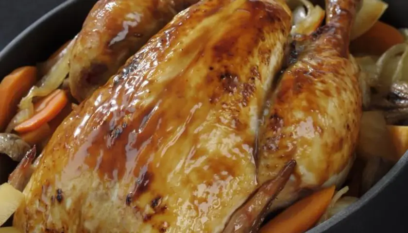 Un poulet rôti doré et juteux, accompagné de carottes et d'oignons. Un délice pour savoir quel vin avec un poulet rôti.