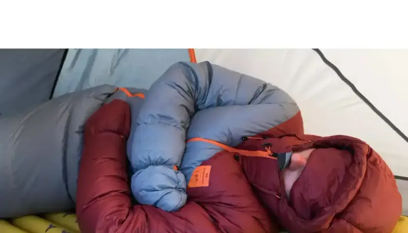 Osoba zwinięta w śpiworze w namiocie. Dobry śpiwór to podstawa komfortowego snu na łonie natury.