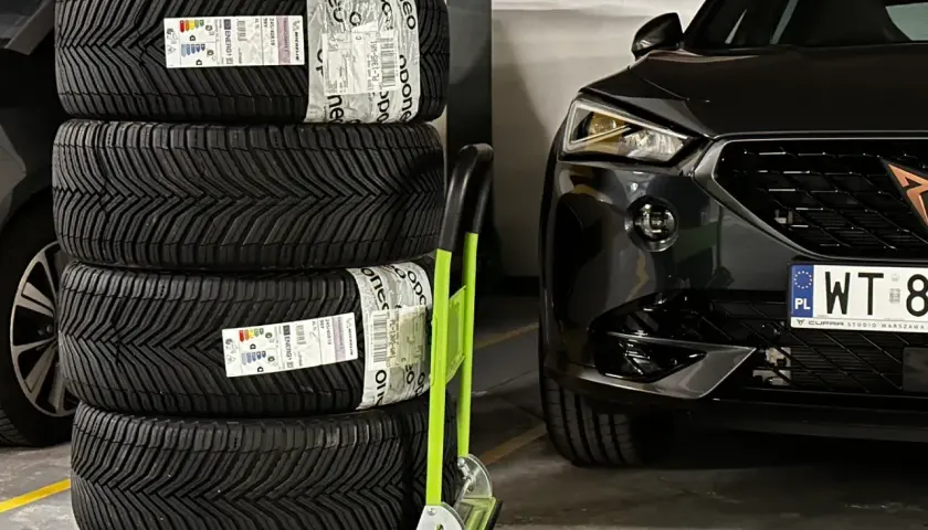 Cztery nowe opony Michelin CrossClimate 2, uznawane za najlepsze opony wielosezonowe, czekają na montaż w czarnym aucie.