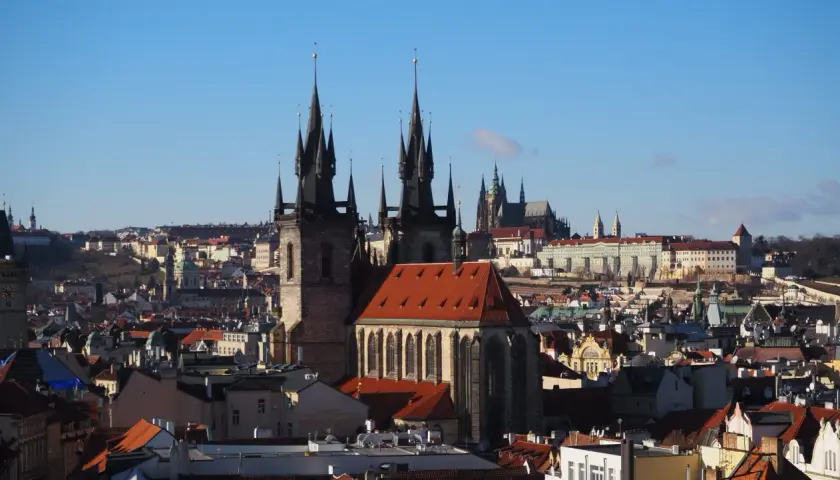 Gotycka wieża w Pradze góruje nad miastem, a w tle widać zamek.