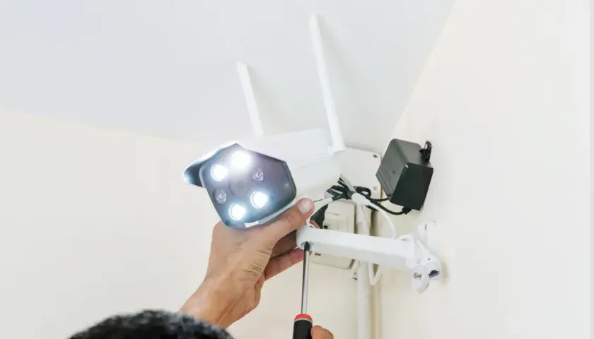 Montaż kamery, która działa tylko na wifi. Ręka przykręca śrubę mocującą urządzenie do ściany.
