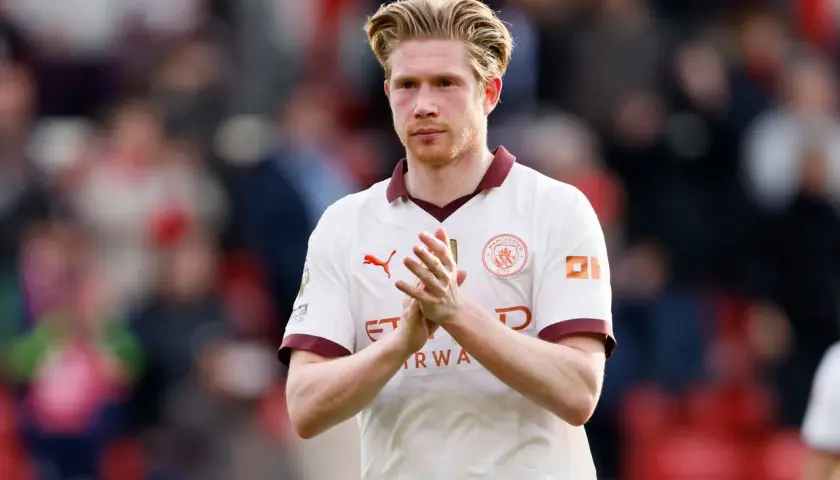 Kevin De Bruyne, w białej koszulce Manchesteru City, klaszcze w dłonie. Jego obecne drużyny to Manchester City.