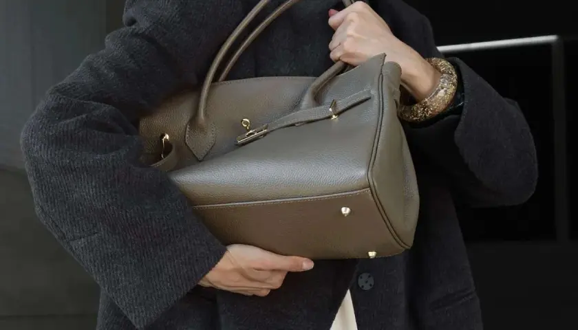 Elegancka, szara torebka na ramię z uchwytami i złotymi elementami. Idealnie wpisuje się w trendy, pokazując, jakie torebki są teraz modne.