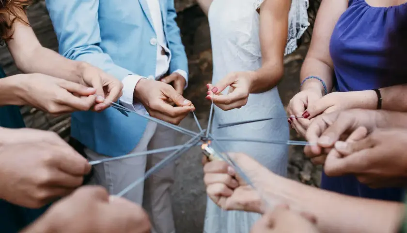 Manos sostienen bengalas formando un círculo, creando un ambiente festivo para juegos para bodas.