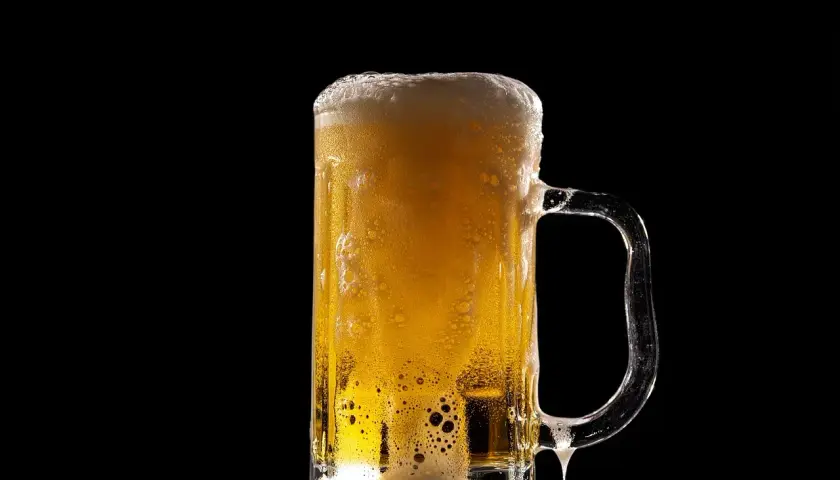 Piana z piwa Lech Pils spływa po szklance, tworząc orzeźwiający widok.