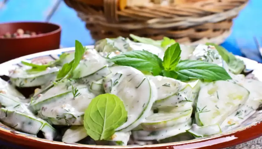 Salade fraîche de concombre à la crème, garnie de menthe et d'aneth. Parfait pour accompagner un concombre au barbecue.