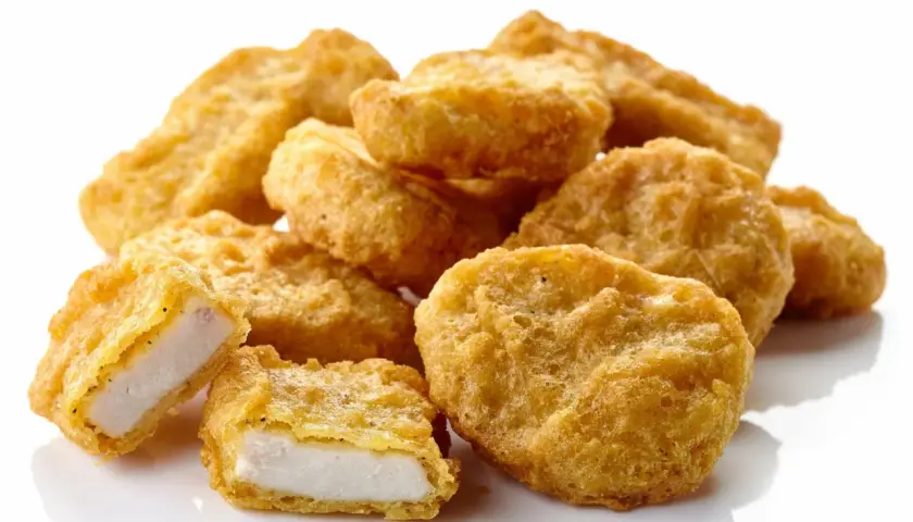 Złociste nuggetsy z kurczaka, jeden przekrojony, ukazujący białe mięso. Ile kcal ma 6 mcnuggets?