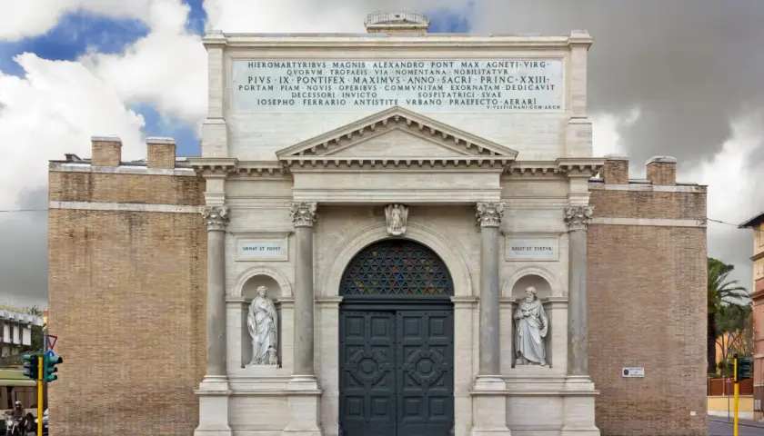 La Porta Pia, con le sue statue e iscrizioni, si erge maestosa sotto un cielo nuvoloso.