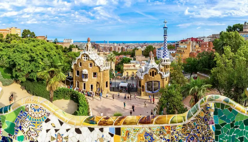 Kolorowa mozaika wita podczas zwiedzania Parku Güell. W tle bajkowe domki i panorama Barcelony.