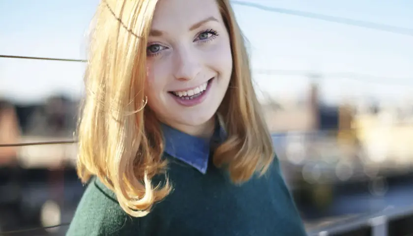 Glad ung kvinna med blont hår ler mot kameran. Hennes sandra beijer ålder är svår att avgöra, men hon utstrålar ungdomlig energi.