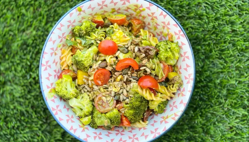 Ensalada de pasta con brócoli, tomates cherry y semillas. Los ingredientes frescos y coloridos la hacen irresistible.