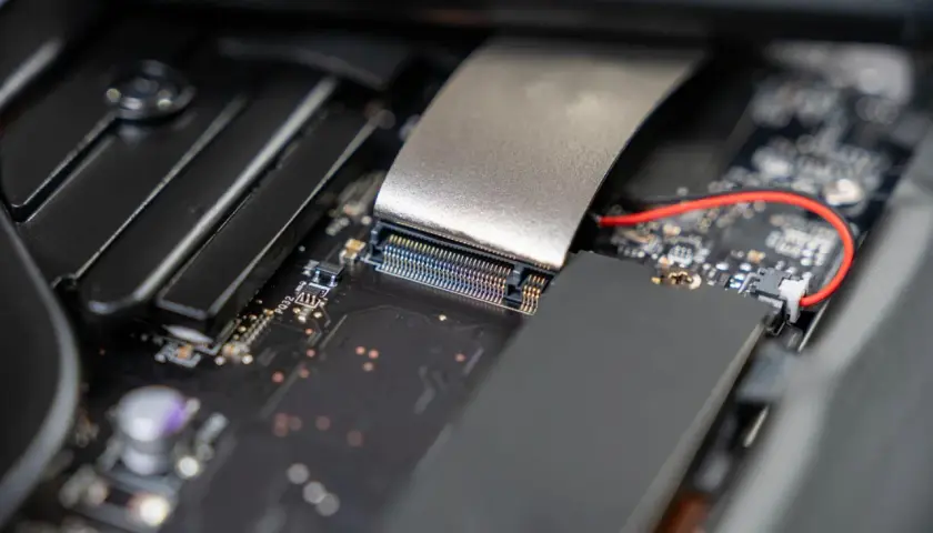 Nahaufnahme eines Motherboards, bereit für die m2 ssd installieren. Ein silbernes Kabel ist mit einem Anschluss verbunden.