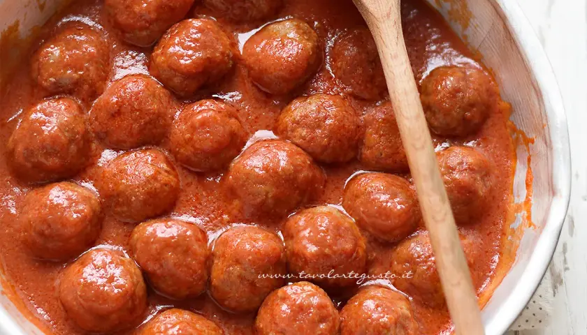 Succulente polpette in padella, immerse in un sugo rosso invitante, pronte per essere gustate.