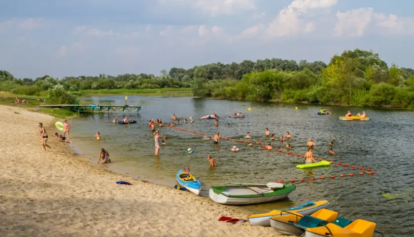 Wola Uhruska tętni życiem. Ludzie kąpią się, pływają na łódkach i relaksują na piaszczystej plaży.