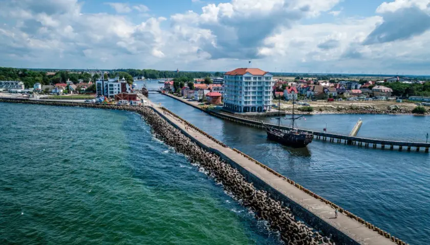 Port w Darłowie z falochronem, statkiem pirackim i nowoczesnym budynkiem. Atrakcje turystyczne na wyciągnięcie ręki.