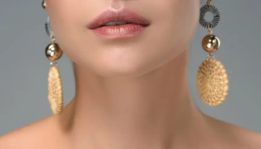 Labios maquillados y pendientes dorados con detalles que recuerdan a tipos de piedras preciosas.