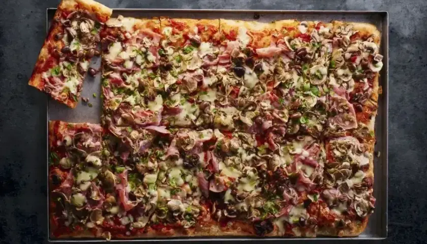 Pyszna pizza domowa przepis na blachę, obficie posypana pieczarkami, szynką i serem. Idealna na rodzinne spotkanie.