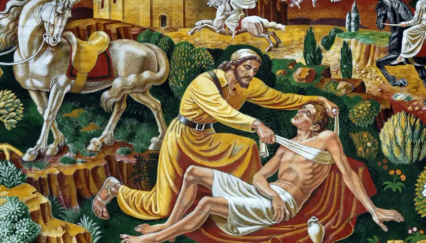 Dobry samarytanin opatruje rannego podróżnego. W tle widać konie i zamek.