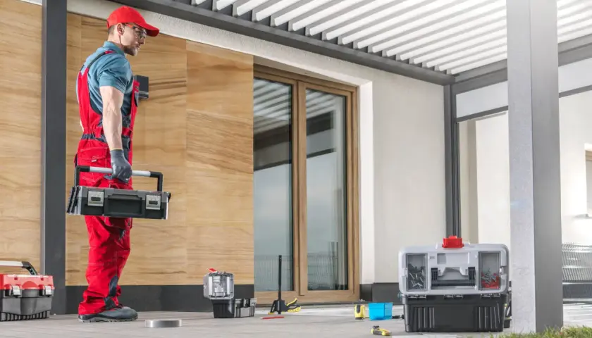 Handwerker mit Werkzeugkasten bereitet sich vor, das Vordach Wandanschluss abzudichten.
