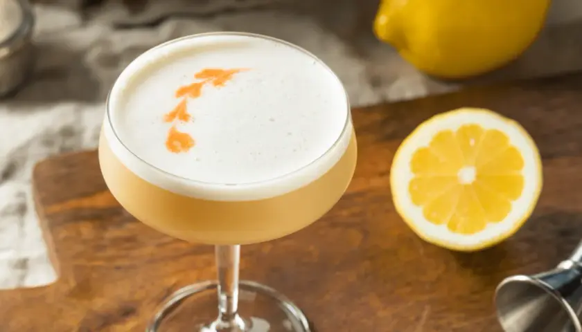 En drink med fluffigt kokosskum och en citronskiva bredvid.