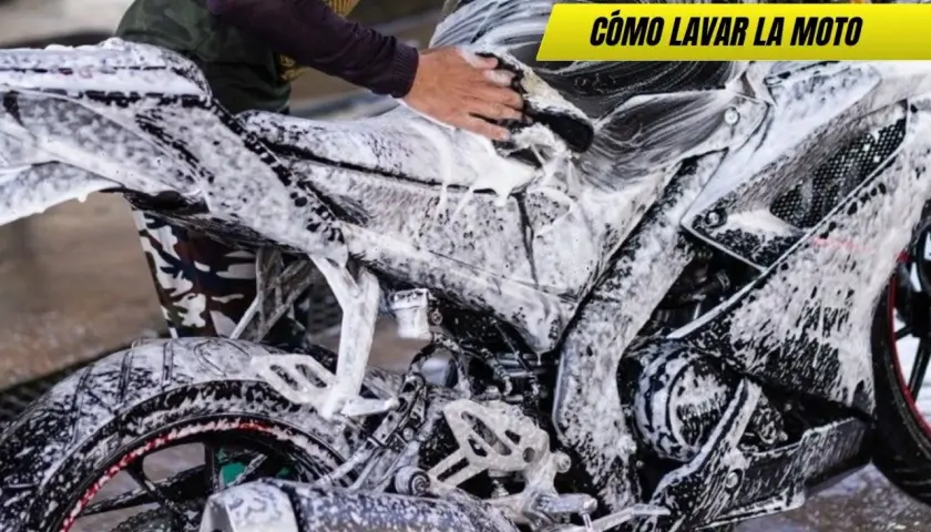 Persona lavando una moto deportiva con espuma. Se ve el motor, la rueda trasera y el tubo de escape. ¡Así se limpia la moto!