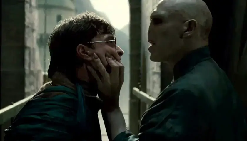 Ralph Fiennes jako Voldemort grozi Harry'emu Potterowi, chwytając go za twarz.