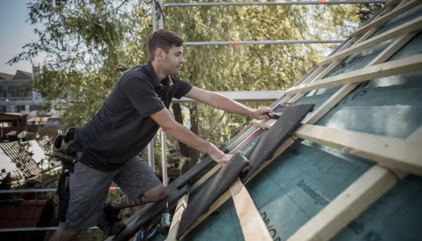 Handwerker verlegt Dachziegel, um die Dachkehle abzudichten.