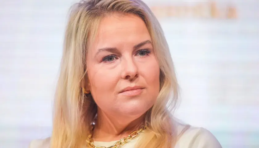 Kamila Kalinczak z blond włosami i złotym naszyjnikiem, patrzy w bok.