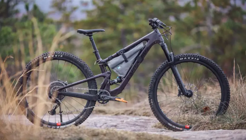 A dark purple Santa Cruz Tallboy 4 mountain bike rests on rocky terrain, ready for an adventure.
