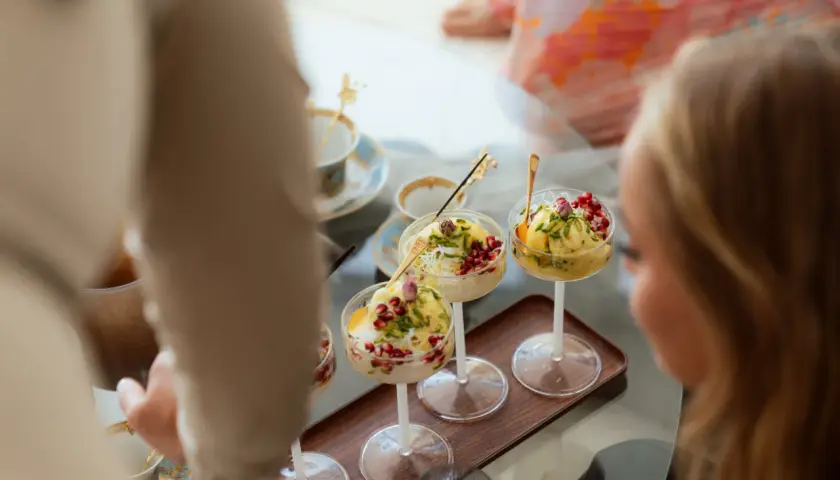 Tre skålar med bastani sonnati, en persisk glassdessert, toppad med granatäppelkärnor och pistasch.