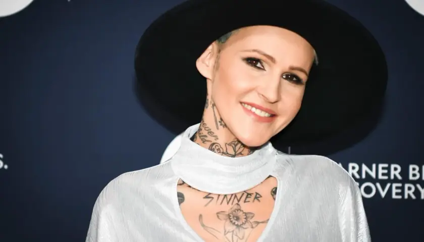 Agnieszka Chylińska w białej bluzce i czarnym kapeluszu, z widocznymi tatuażami na szyi i klatce piersiowej.