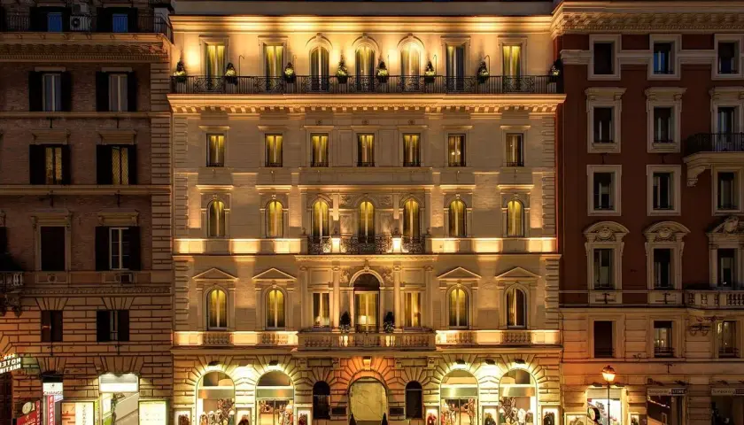 Edificio illuminato di notte, con negozi al piano terra, nel quartiere Esquilino a Roma.