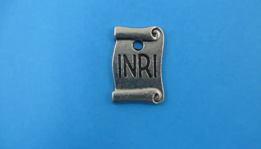 Metalowy zwój z napisem INRI, symbolizujący tabliczkę z krzyża.