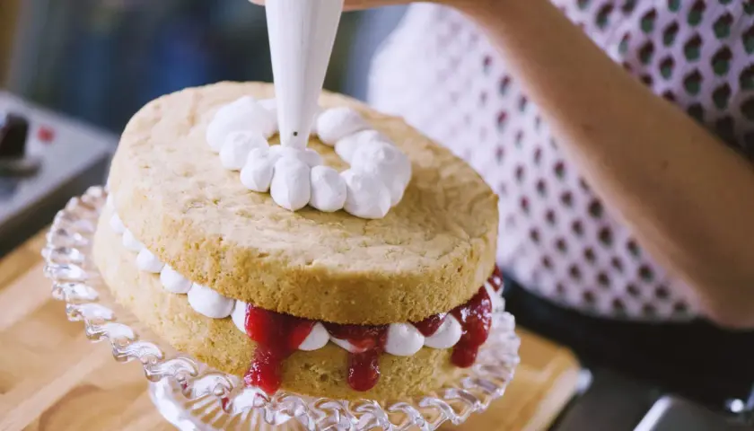 Decorazione di una torta con panna fresca montata. La differenza tra panna fresca e panna da cucina è evidente nella consistenza e nel risultato finale.