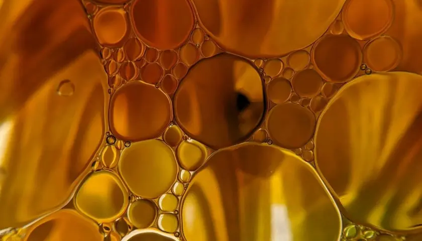 Gotas doradas y ámbar flotan juntas, creando un patrón hipnótico que te hace soñar con aceite.