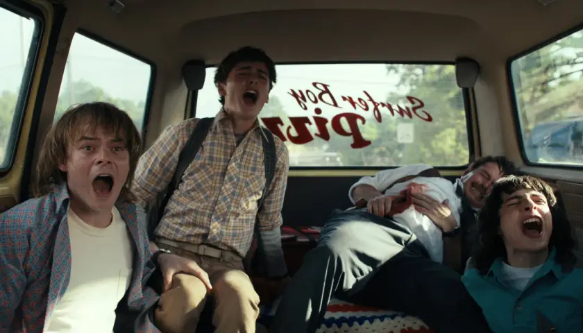 Czterech przerażonych przyjaciół z Stranger Things 4 krzyczy w vanie, gdy przejeżdżają obok Surfer Boy Pizza.