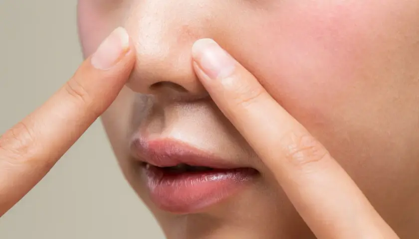 Dłonie dotykają nosa, ukazując pory i zaczerwienienie. Czy to nadmiar sebum?
