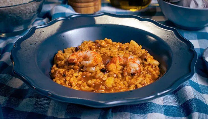 Un plato de paella mixta con gambas y arroz dorado, listo para disfrutar.