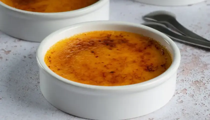 Dwa białe naczynia z pyszną, skarmelizowaną górą. Idealna crema catalana, gotowa do rozkoszowania się.