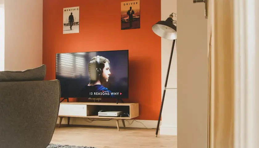 Pomarańczowe ściany świetnie komponują się z szarością kanapy i dywanu. W salonie wisi plakat z filmu "Driver".