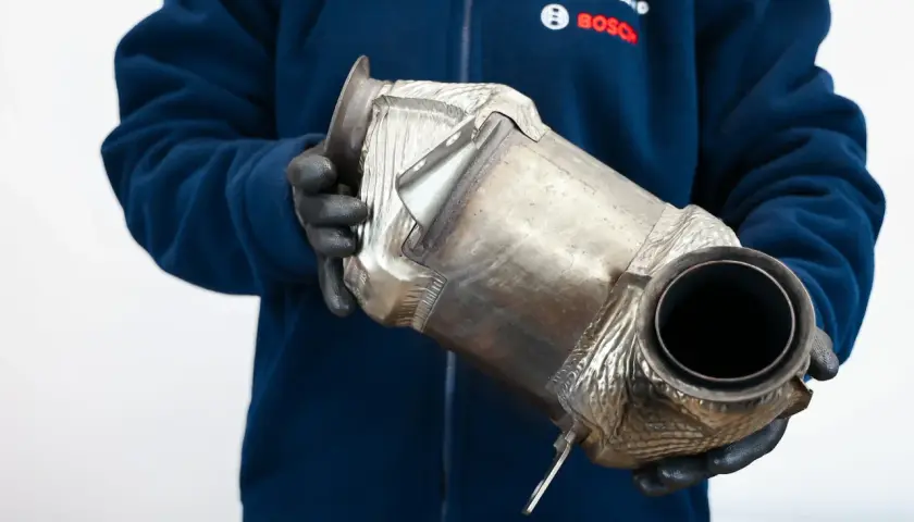 Mechanik w rękawiczkach trzyma filtr DPF. Czy DPF to katalizator? To pytanie często zadawane przez kierowców.